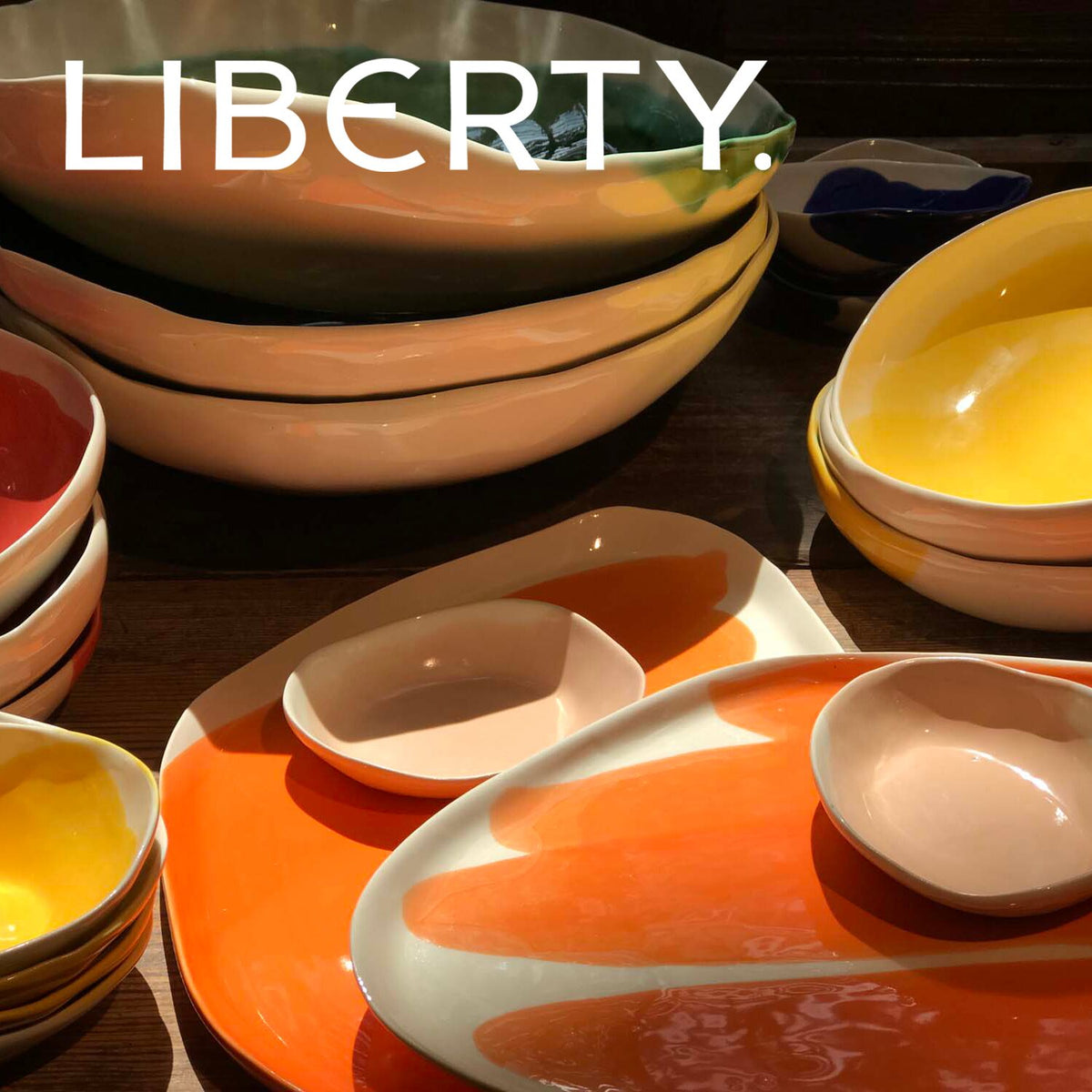Pottery & Poetry handmade ceramic bowls and platters in orange and yellow on display at Liberty London