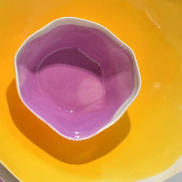 Pink glazed ceramic bowl on a yellow background, viewed from above