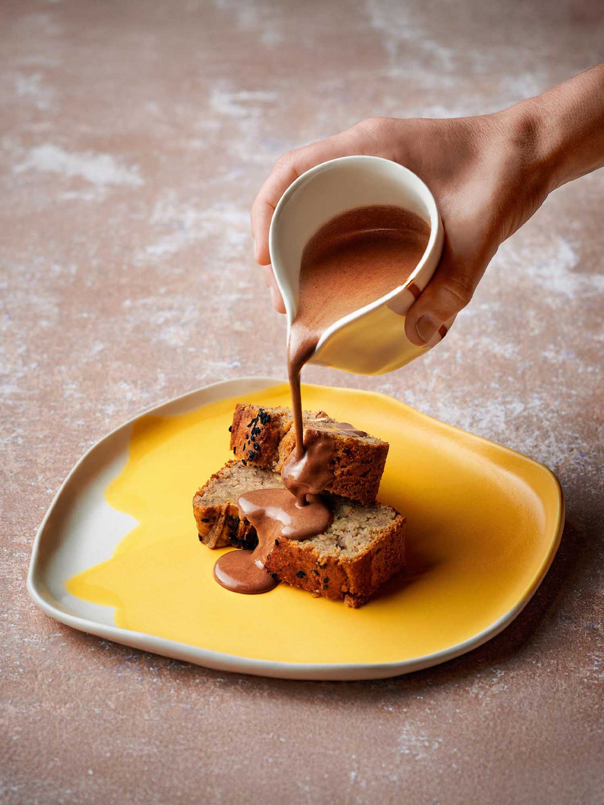 Chocolate sauce poured over cake on a yellow glazed porcelain plate from a ready-made restaurant collection