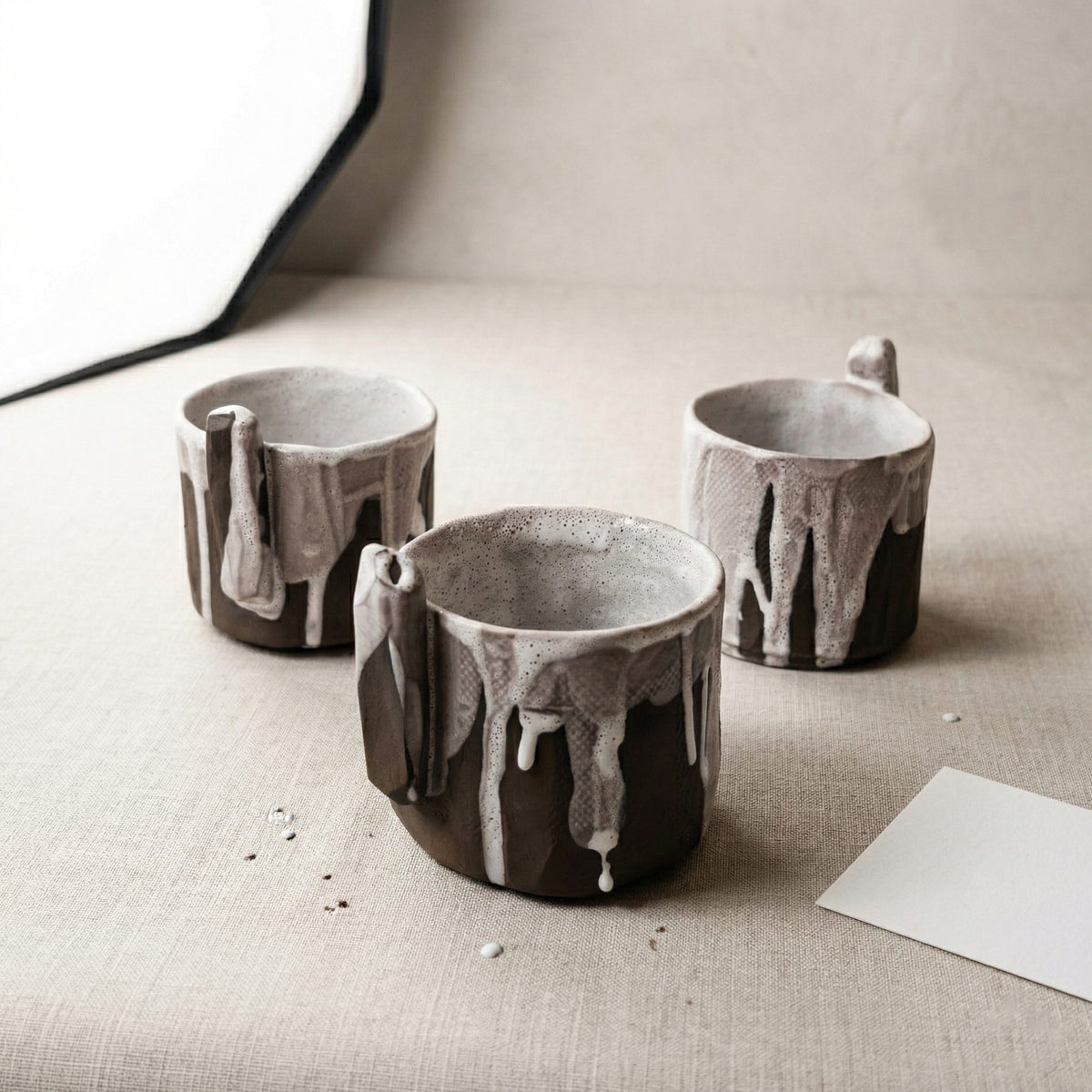 Three black clay cups with dripping white glaze, part of the Chef's Table restaurant collection