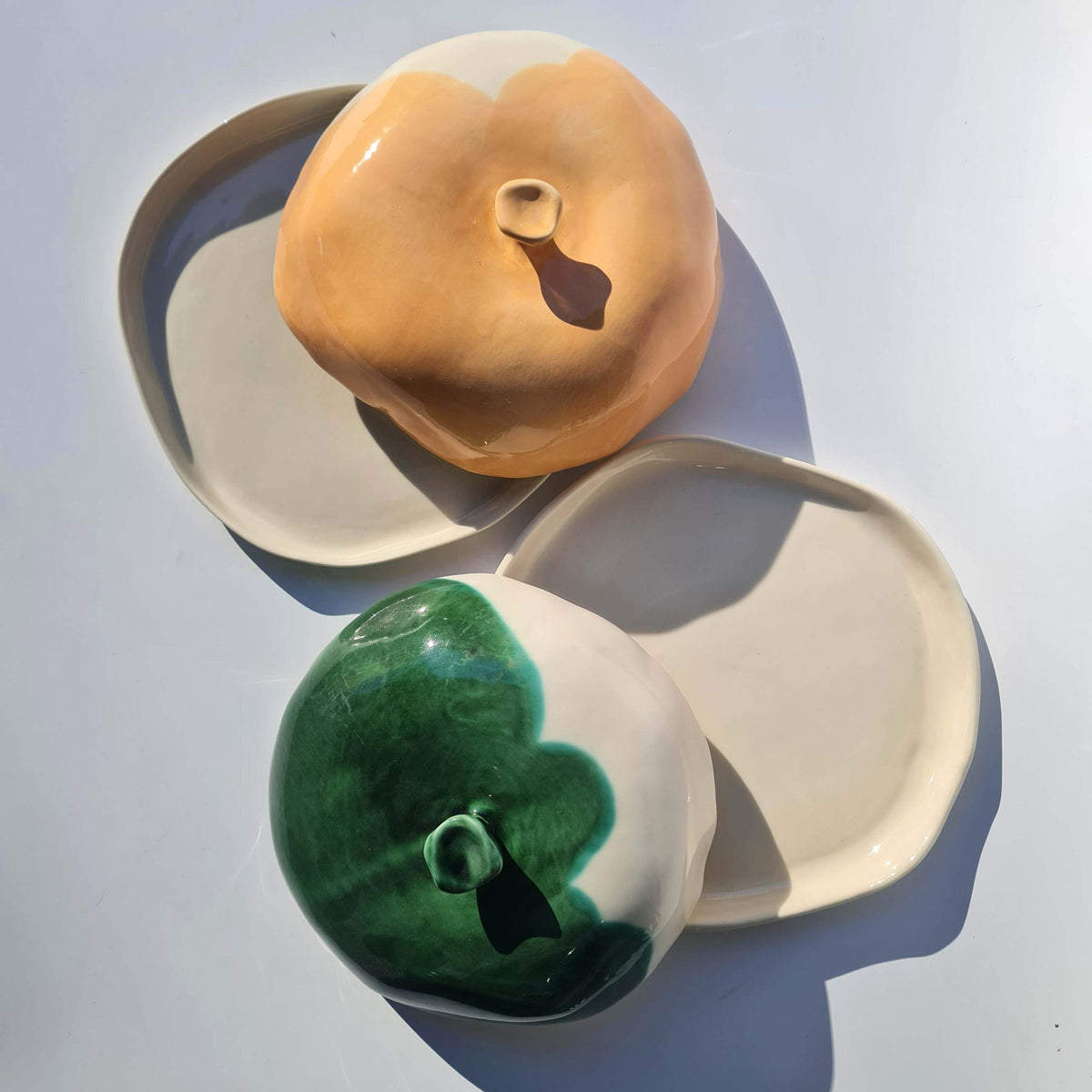Green and ochre ceramic cheese-box lids beside ivory serving plates