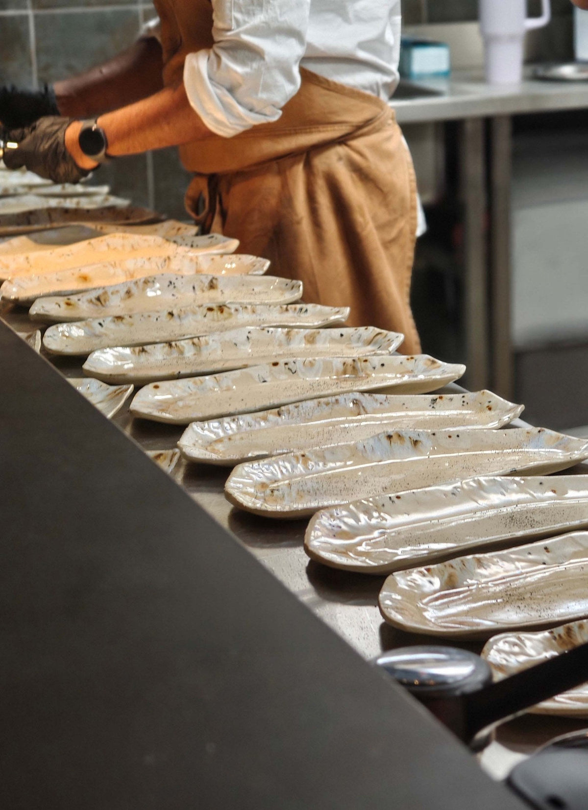 Row of handmade Salon plates on the pass in the restaurant kitchen