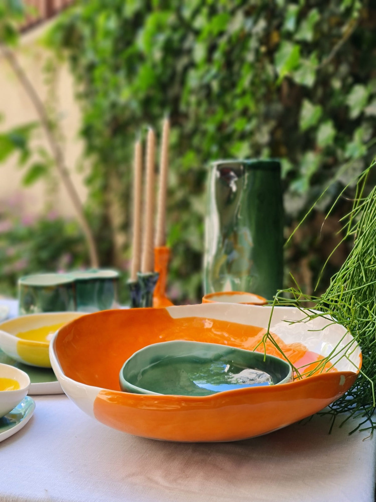 Orange and ivory porcelain serving bowl with a green bowl inside, set on an outdoor table