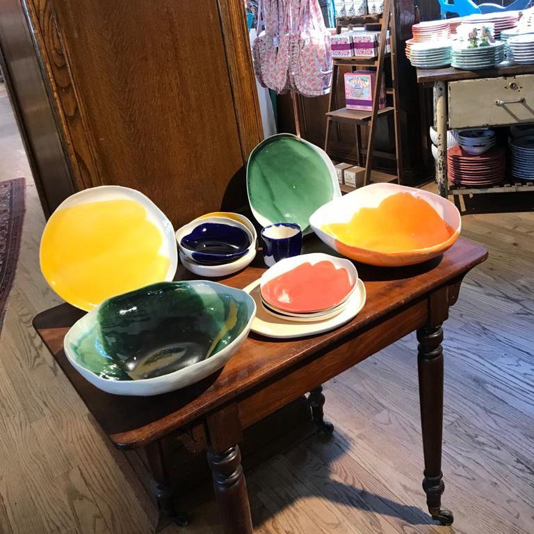 Colourful handmade porcelain serving bowls displayed on a wooden table at Liberty London