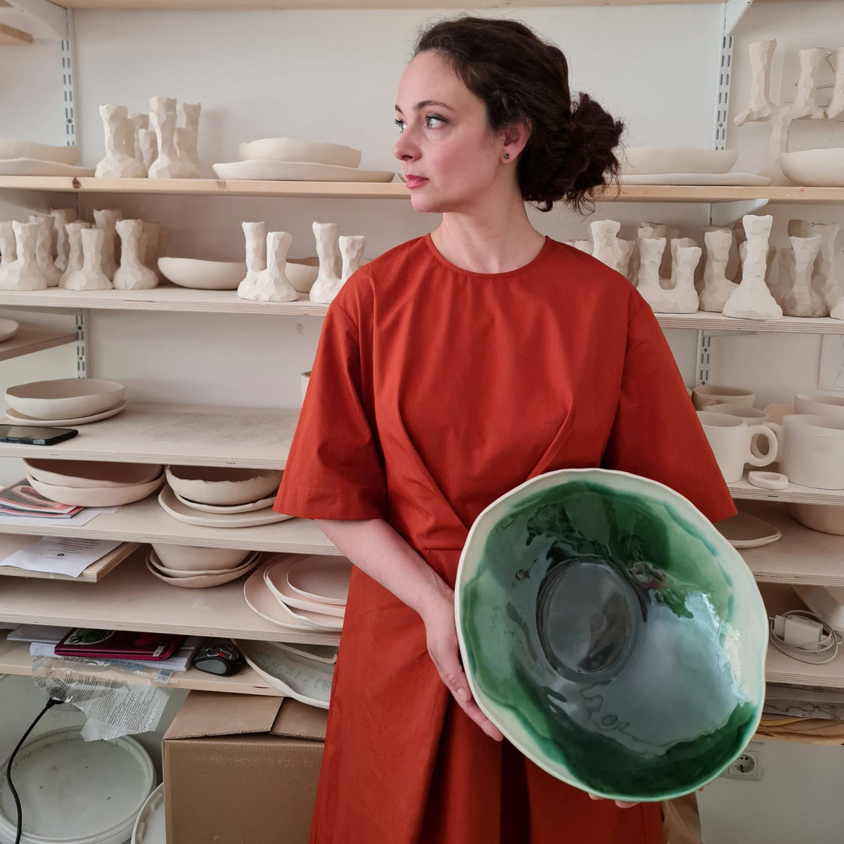 Maria Baleva in her Sofia studio holding a large green porcelain serving bowl