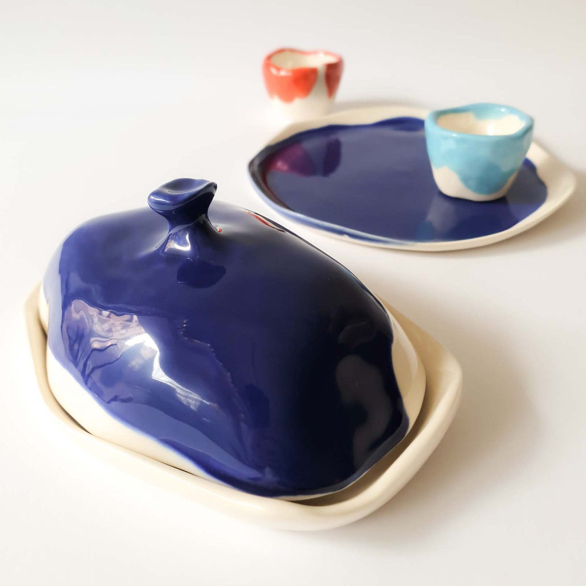 Porcelain butter dish with Royal Blue glazed lid, matching plate and small cups in blue and red