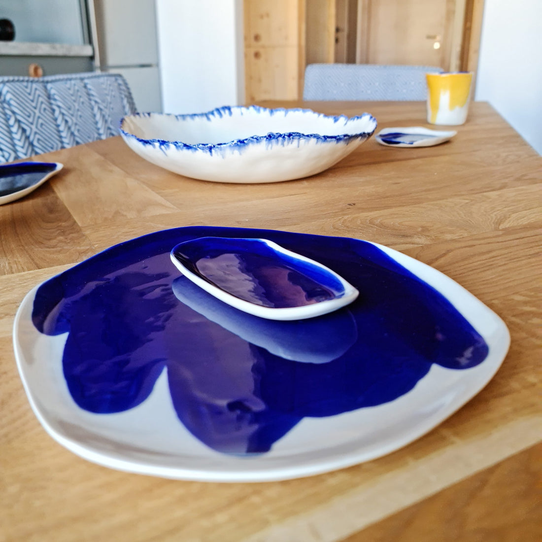 Royal Blue glazed porcelain plate, serving dish and bowl with blue brushed rims on a wooden table