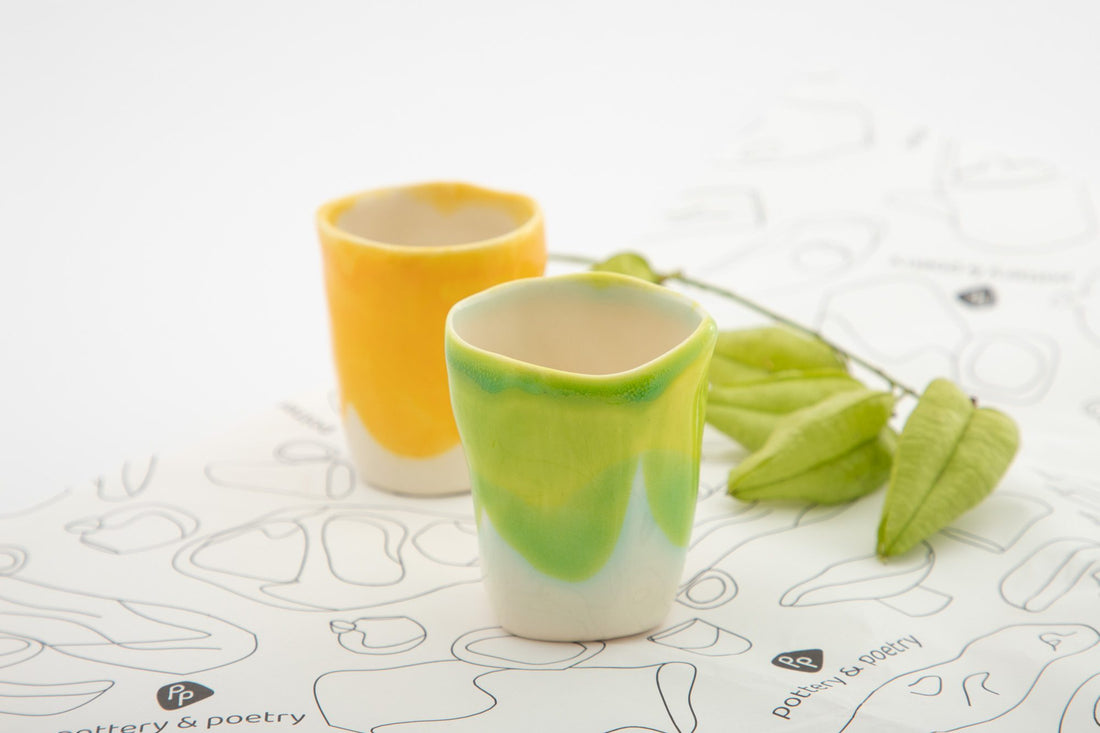 Yellow and green handmade espresso cups on a patterned surface