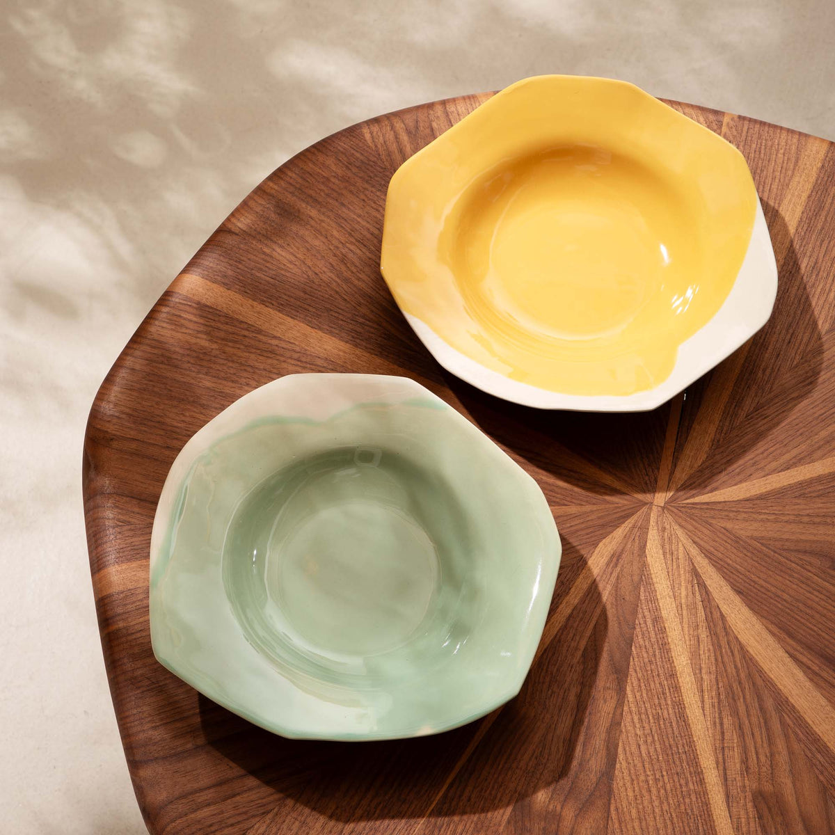 Yellow and pale green handmade deep plates on a round wooden tray