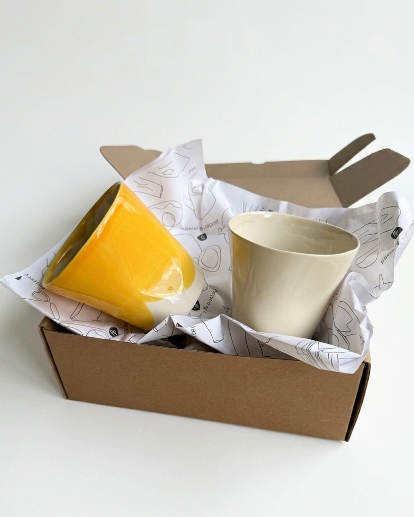 Set of 2 Large Cups in yellow and ivory glaze unpacked from a kraft gift box with tissue