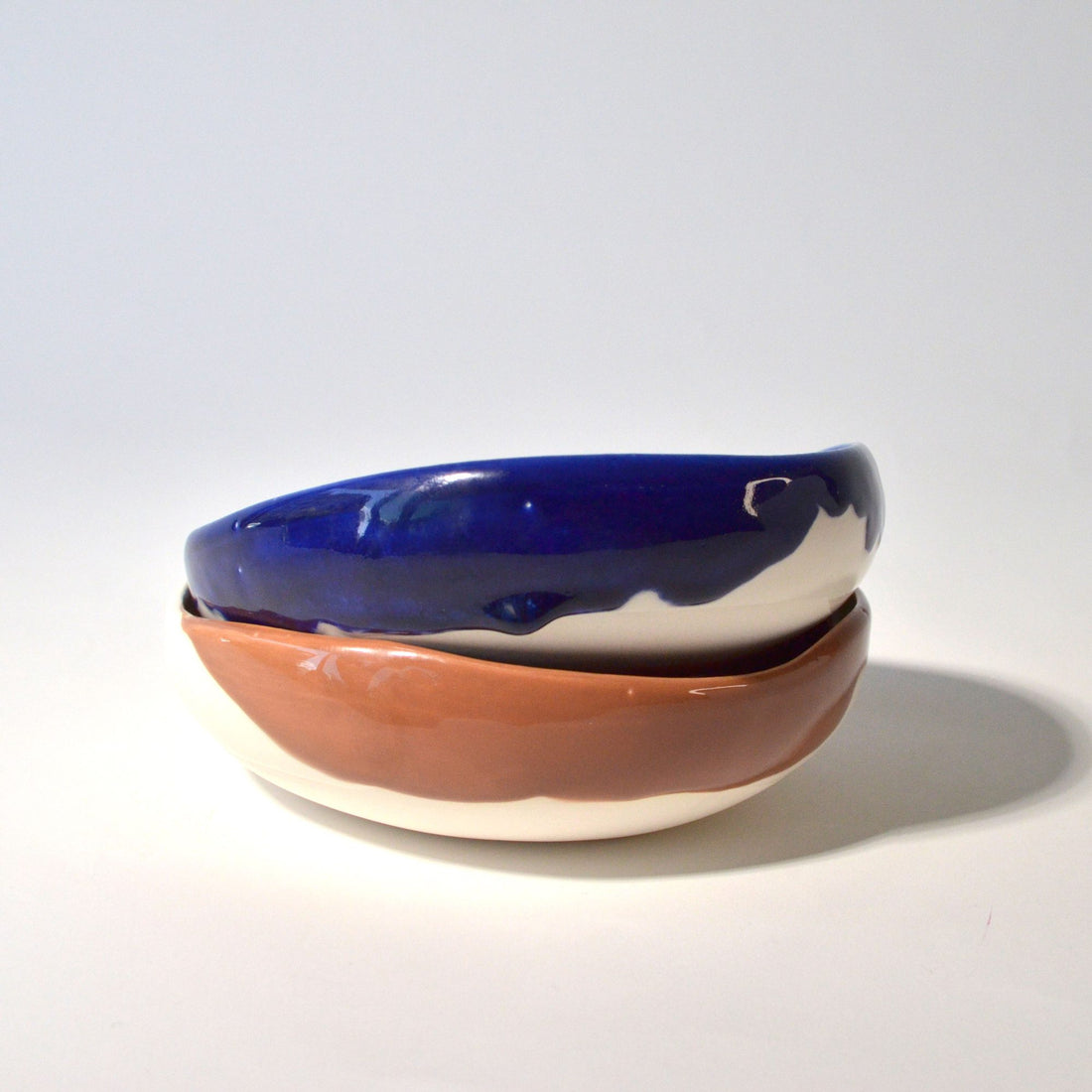 Two stacked round ceramic bowls with royal-blue and terracotta glazes