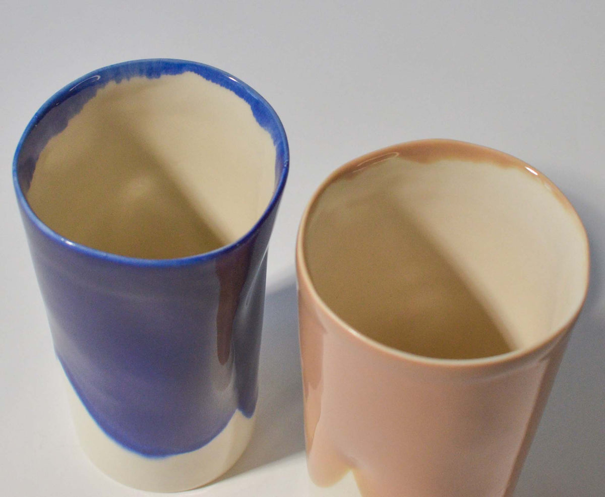 Close-up of the irregular rims and ivory interiors of blue and peach ceramic cups