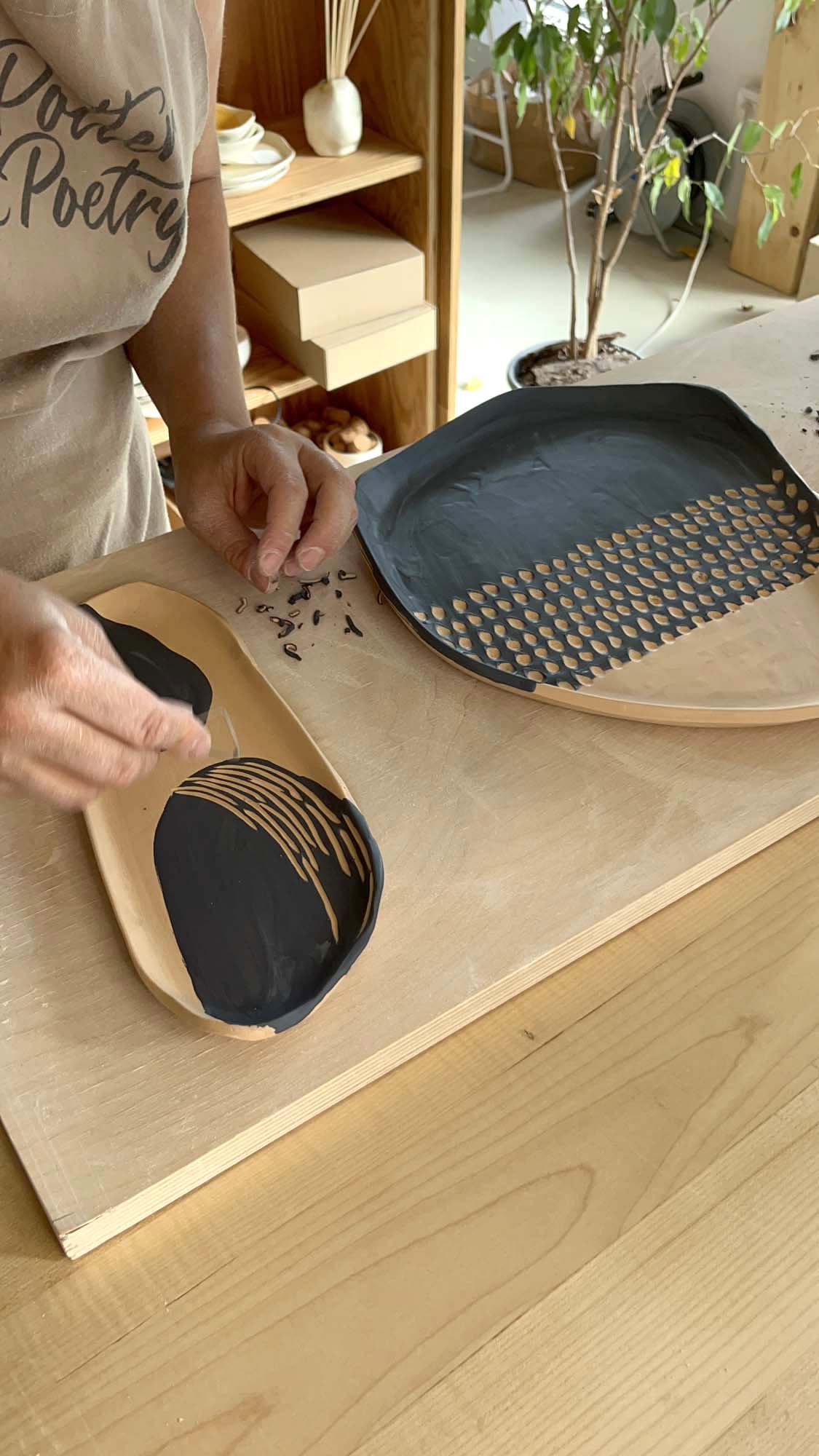 Workshop guest carving a sgraffito pattern into a blue-glazed platter at Pottery & Poetry