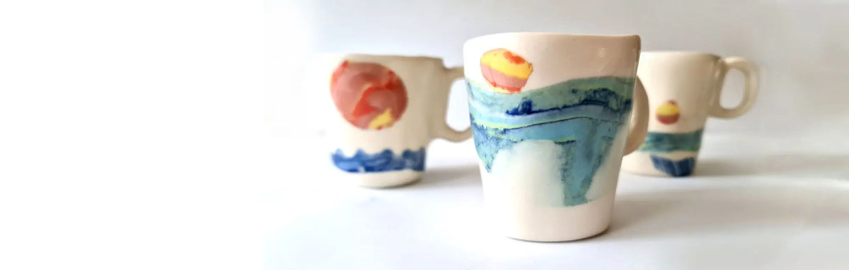 Handmade porcelain mugs with painted blue, orange and turquoise glaze on display