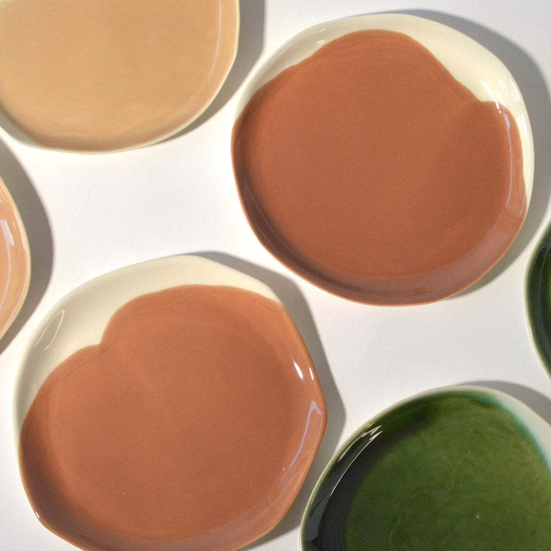 Porcelain side plates in Hazelnut glaze with white rims beside peach and green ceramic plates