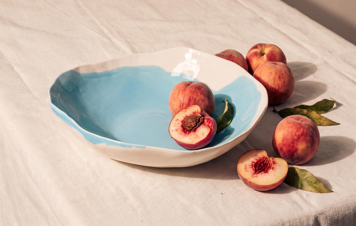 Sky Blue glazed handmade porcelain bowl with an organic rim, served with fresh peaches on linen