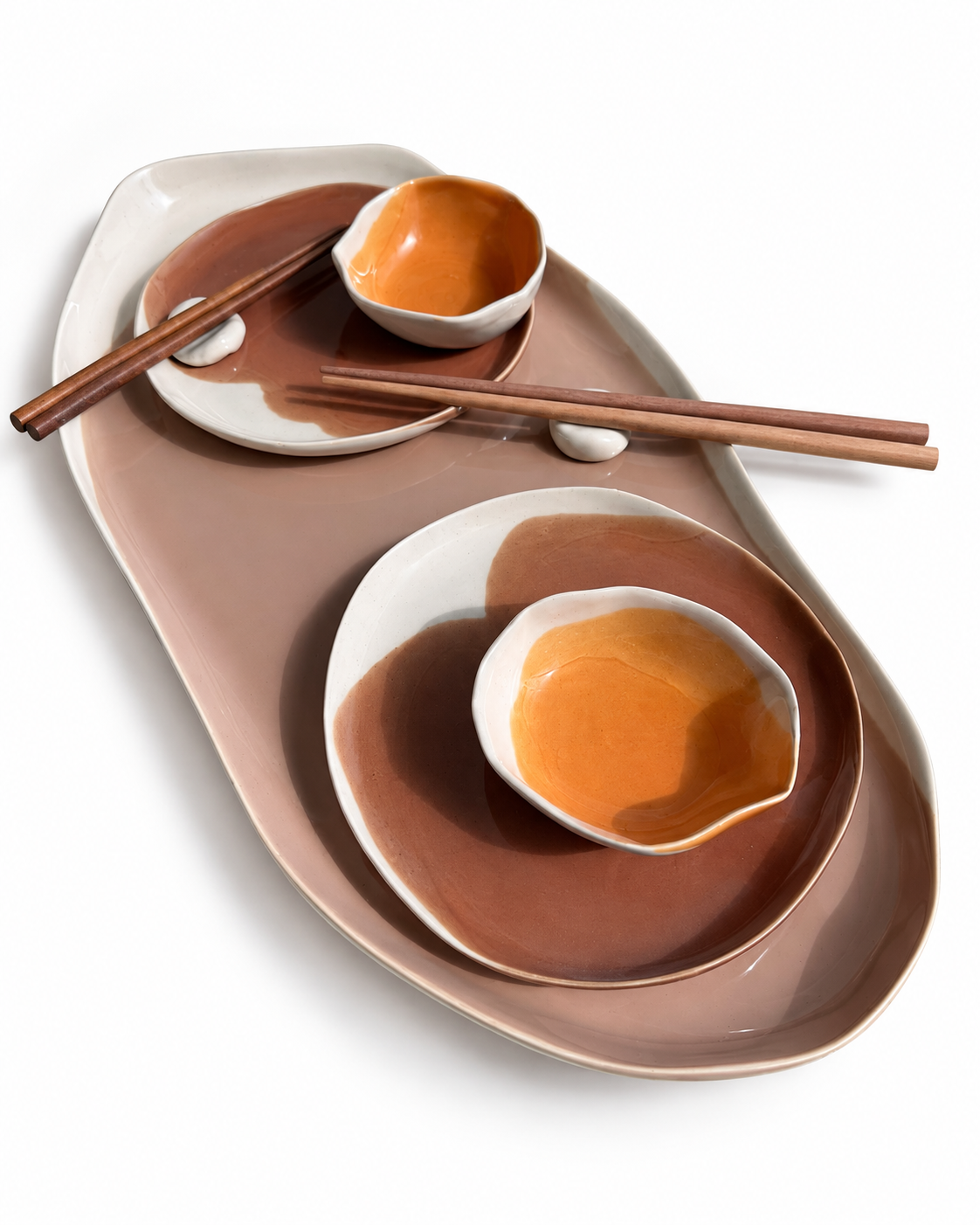 Close-up of a brown ceramic sushi platter, matching plates and orange dip bowls
