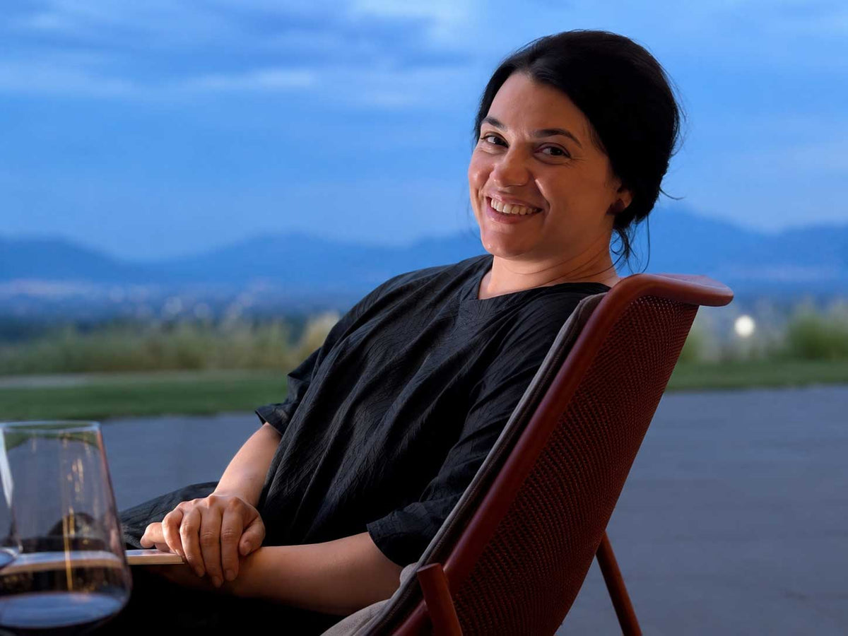 Maria Kisselova, ceramicist at Pottery & Poetry, smiling on a terrace with a glass of wine at dusk