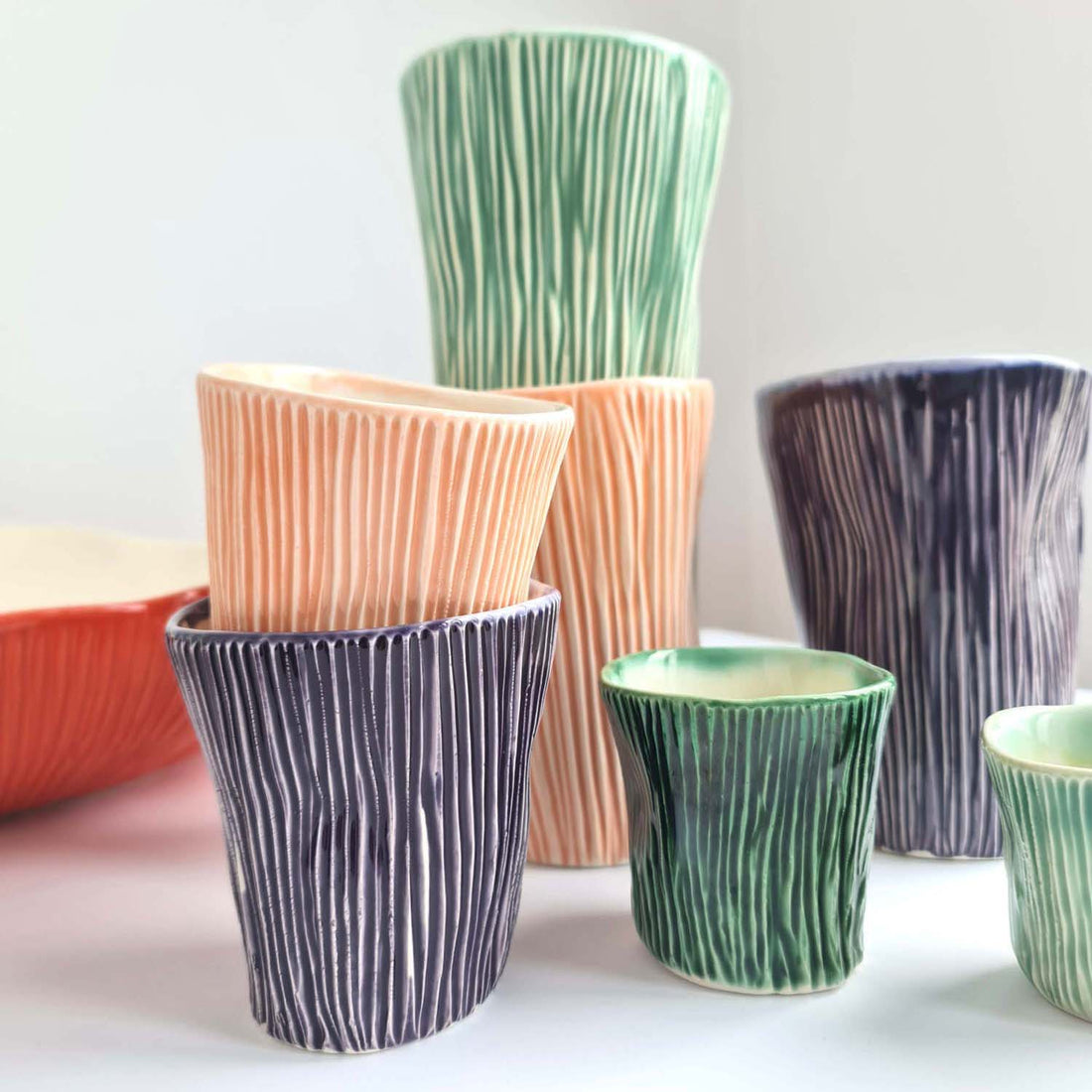 Textured ceramic cups in several heights and green, peach and purple colours