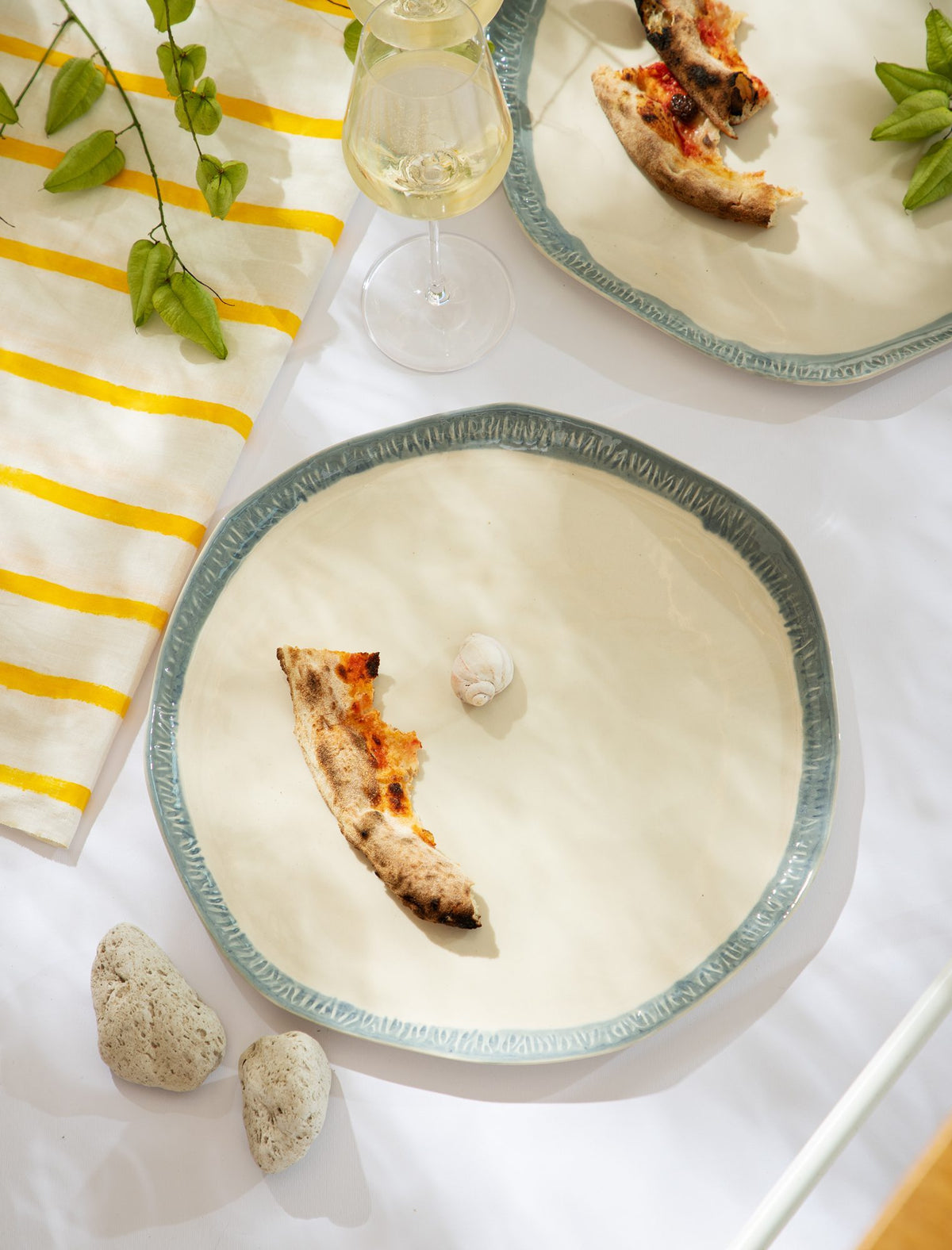 Pizza slices on large ivory ceramic plates with textured green rims