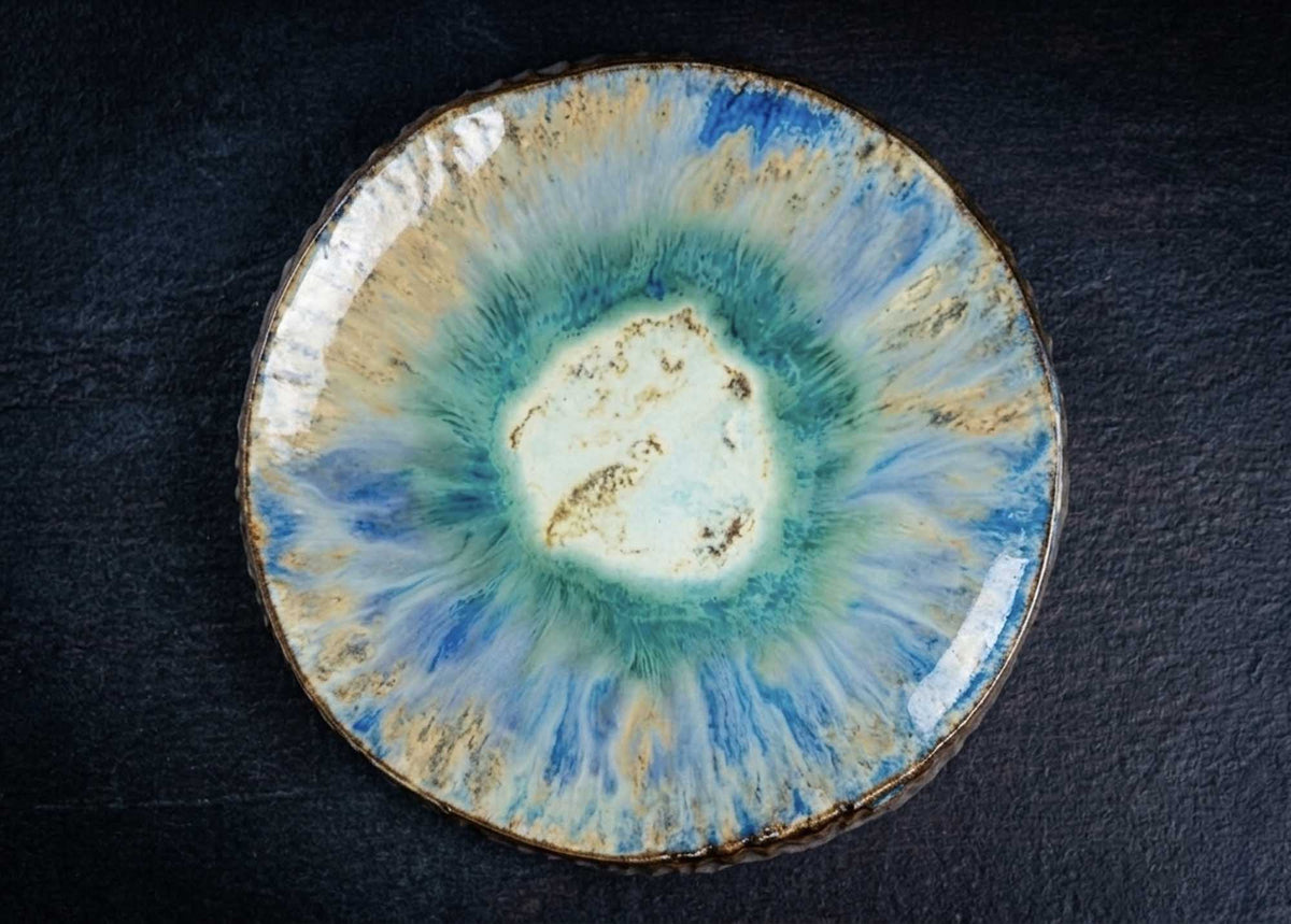 Textured Plate from Black Clay in cream, teal and blue reactive glaze on a dark background