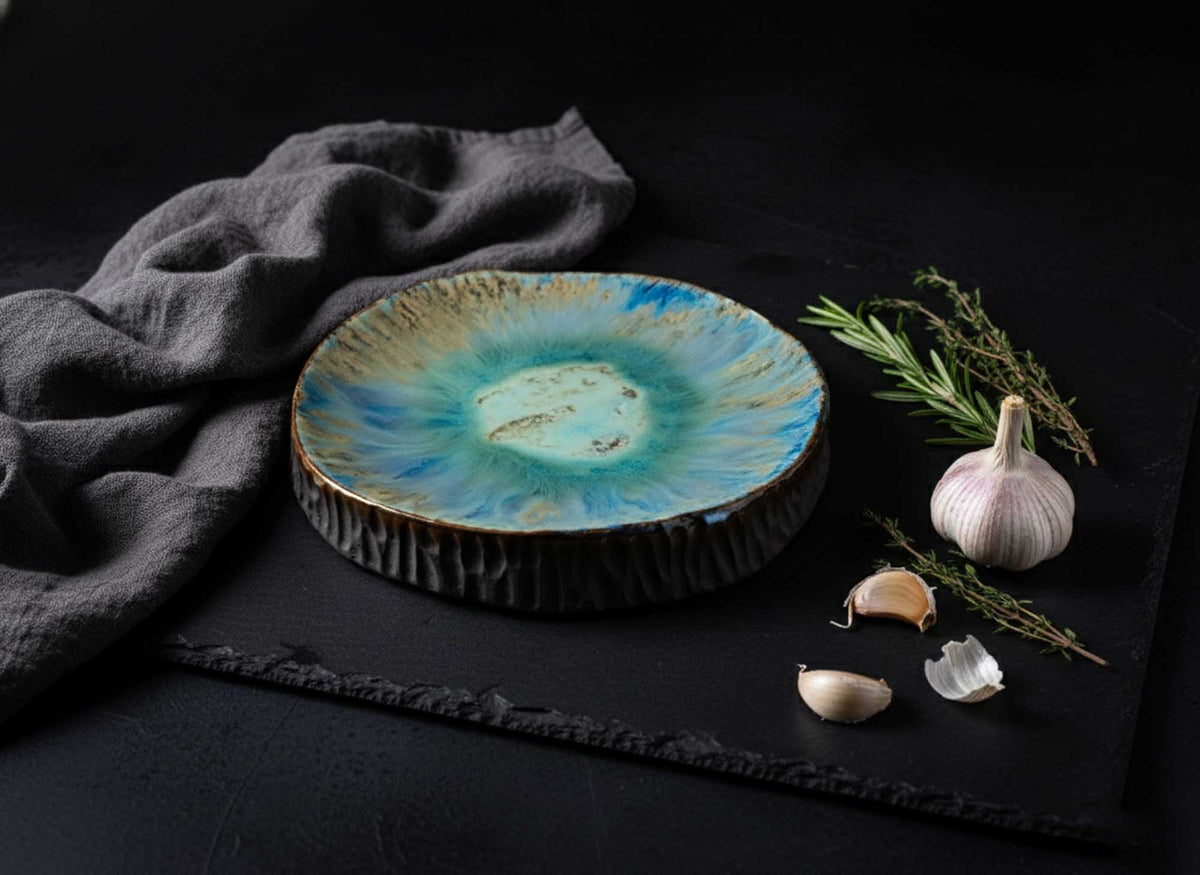 Textured Plate from Black Clay with turquoise glaze on slate beside garlic and rosemary