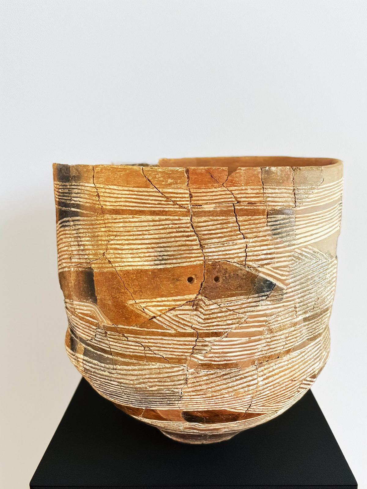 Ancient terracotta vessel with incised horizontal lines, showing the 7,000-year-old sgraffito tradition