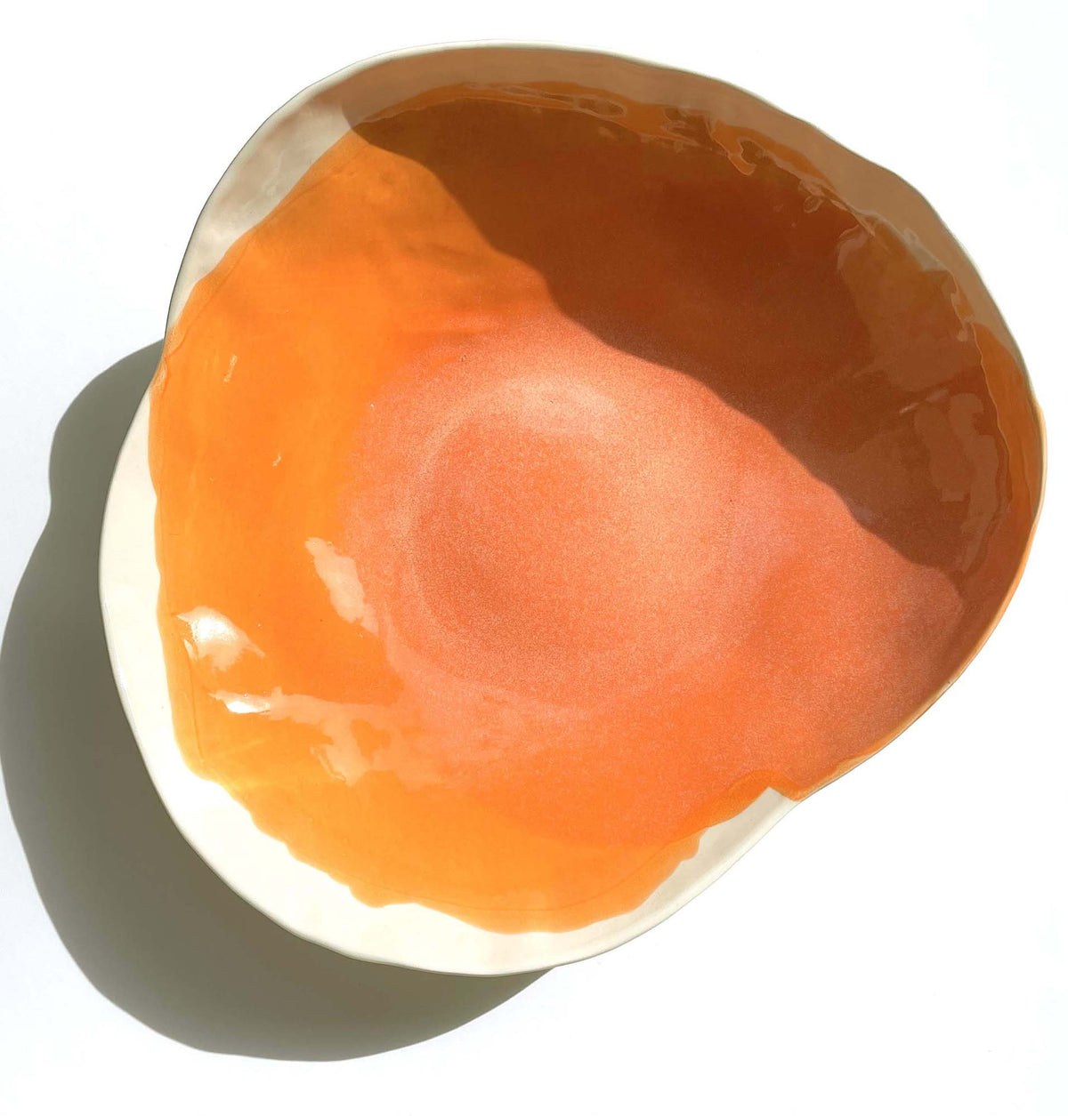 Handmade porcelain serving bowl in Mandarin Orange glaze with an ivory rim, seen from above