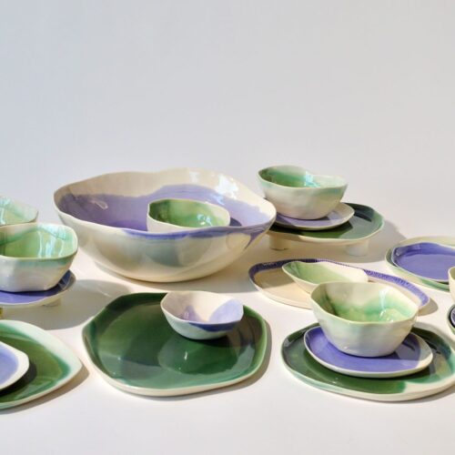 6-person porcelain dinner set in lavender and green tones, plates, bowls, and serving pieces with organic shapes.