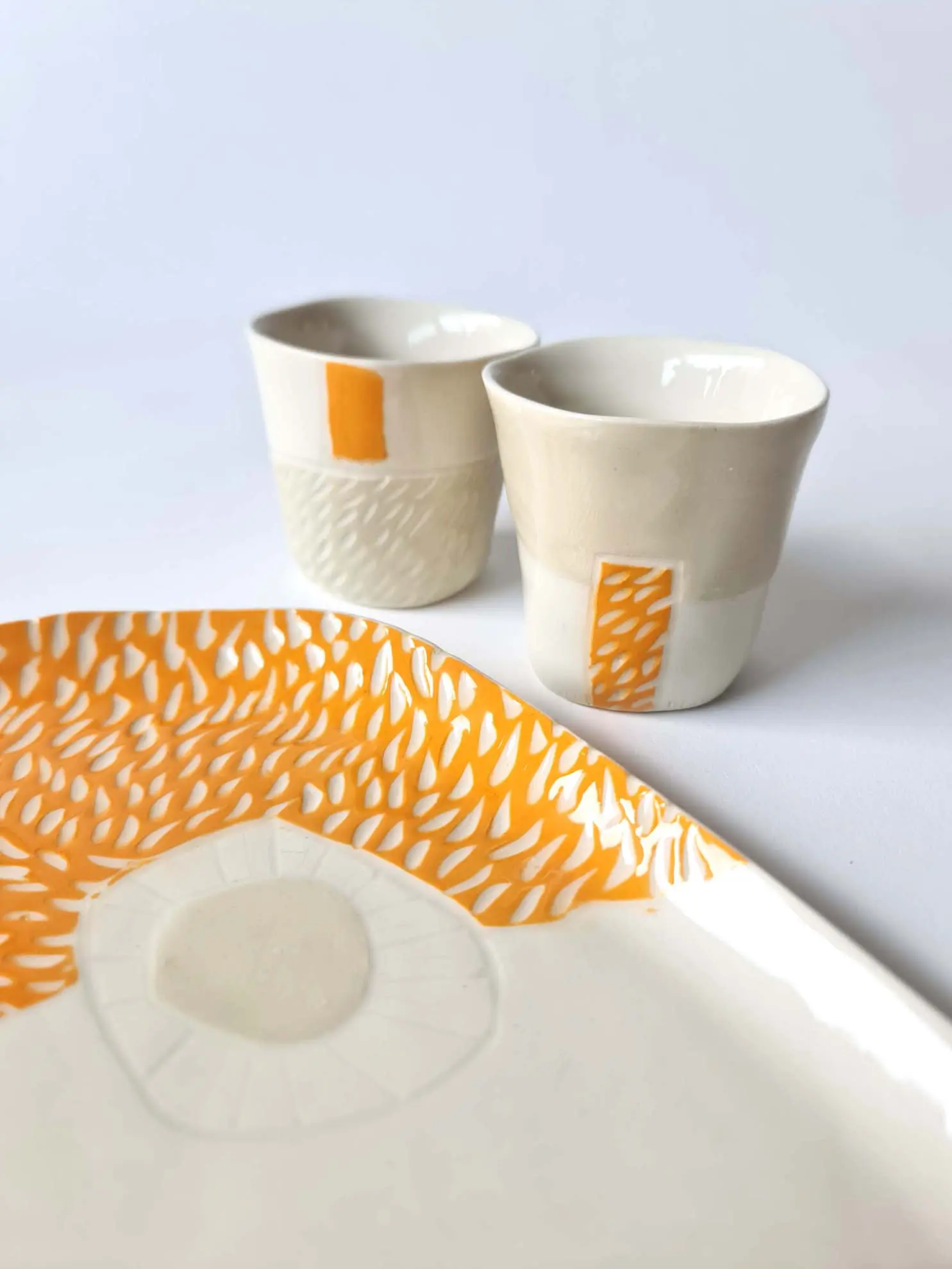 SGRAFFITO-set-2-tray-and-2-cups-7.jpg Handmade porcelain tray and two cups with orange sgraffito detailing on a white background.