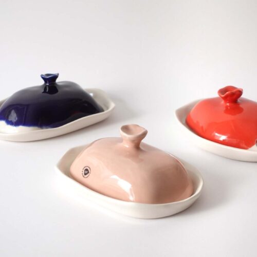 Handmade porcelain butter dishes in red, pink, and navy with sculptural lids
