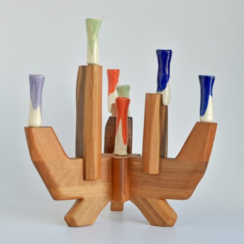 Colorful wooden candelabra with sculptural porcelain candle holders in various glazes.