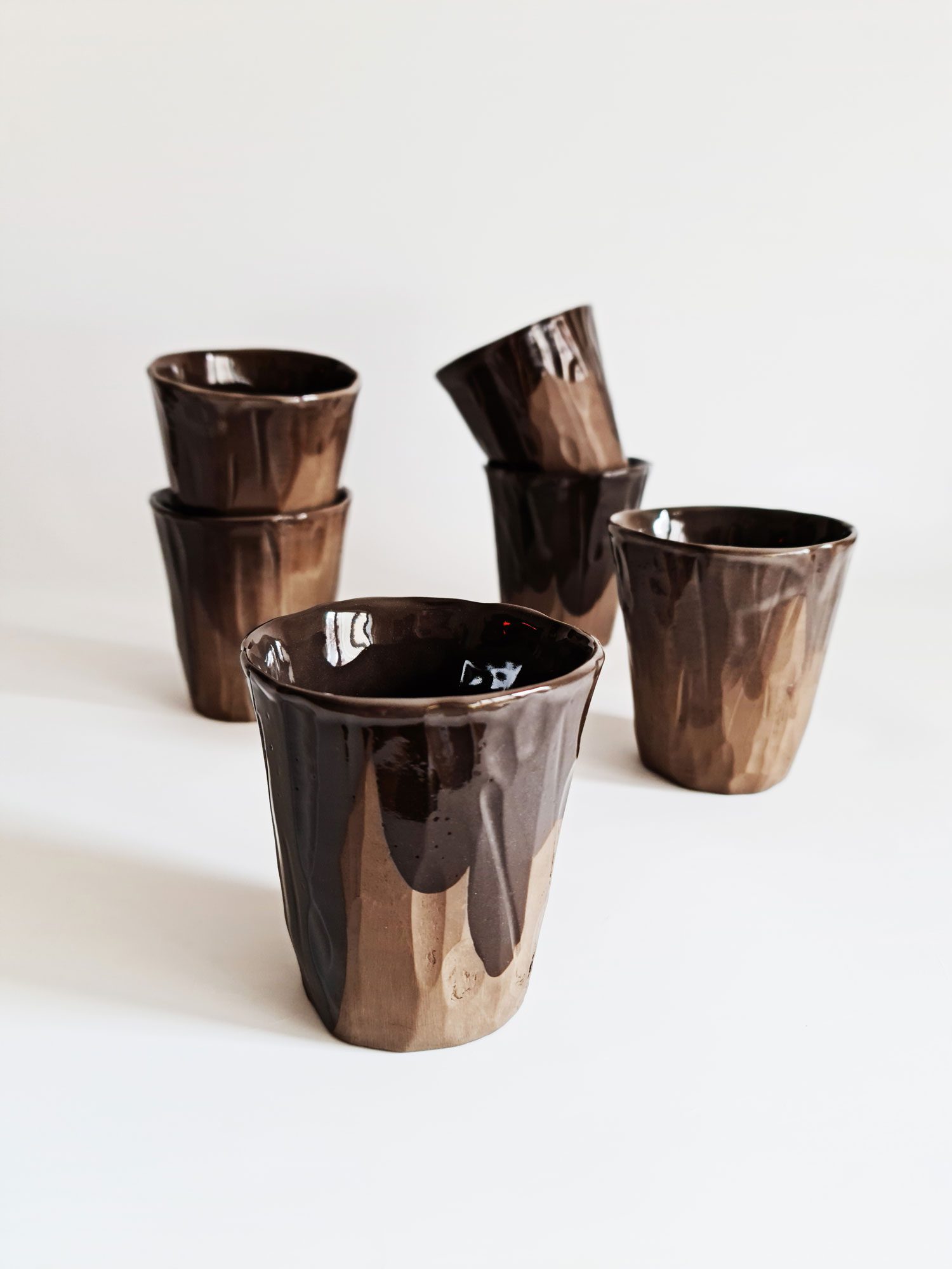 Handmade porcelain drinkware including cups and tumblers.