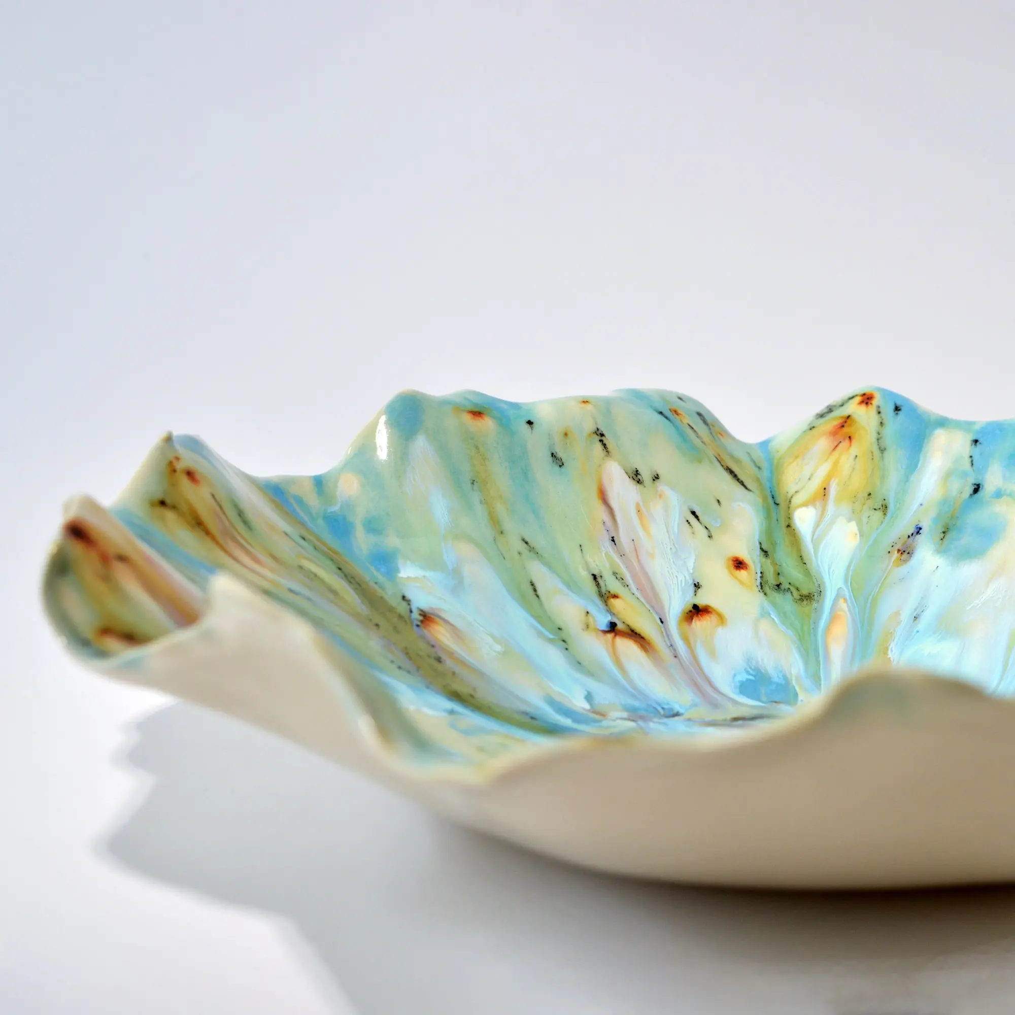 sea-reflections-collection-02.jpg Ruffled porcelain bowl with blue, white, and amber glaze from the Sea Reflections collection.
