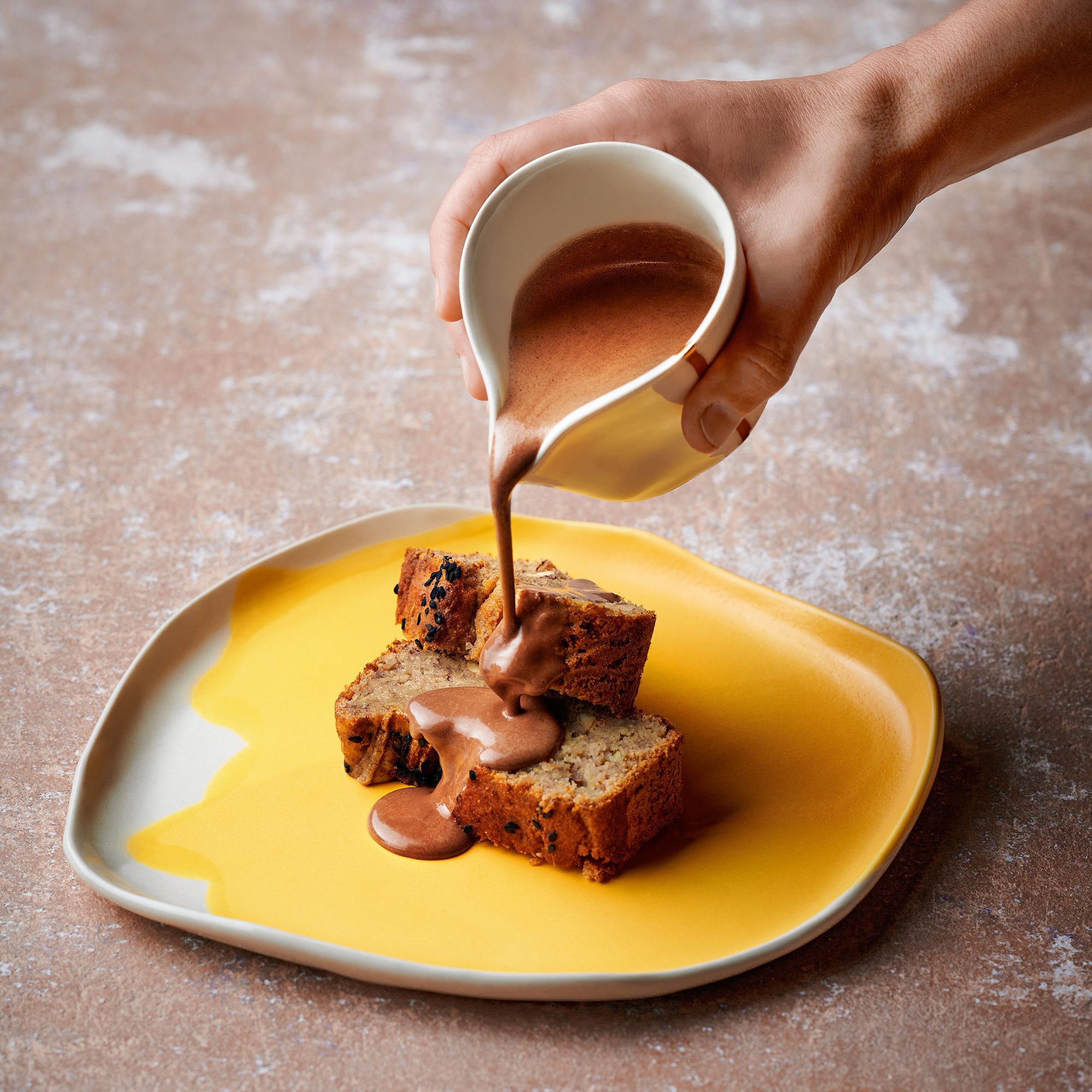 Handmade yellow porcelain plate with banana bread and chocolate sauce.
