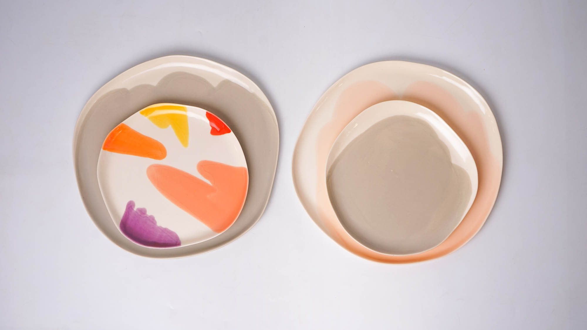 multicolord collection (24) Two sets of layered porcelain plates — one with multicolored brushstrokes, the other in soft neutral tones.
